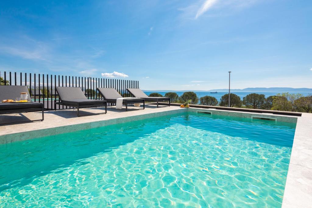 ein Pool mit blauem Wasser und zwei Stühlen in der Unterkunft Luxury Villa Ole with Pool in Kostrena