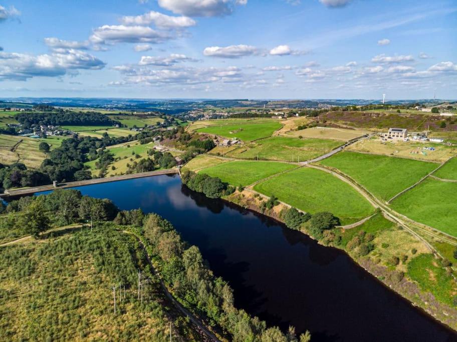 an aerial view of a river with a bridge at Cozy rural lodge, amazing views close to Holmfirth in Holmfirth