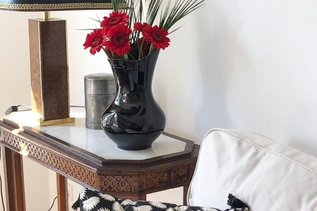 un vase noir avec des fleurs rouges sur une table dans l'établissement La Petite Amélie, à Aix-les-Bains