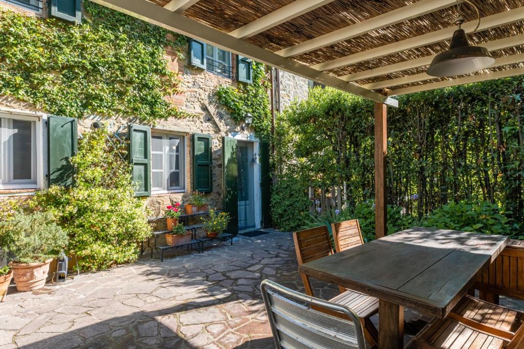 un patio al aire libre con mesa de madera y sillas en Abbacca-là appartamento 2, en Lucca