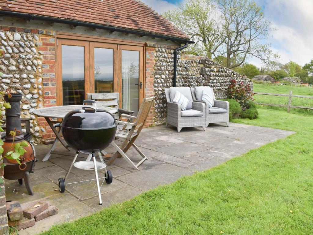 a patio with a grill and a table and a chair at The Cow Shed in Hooe