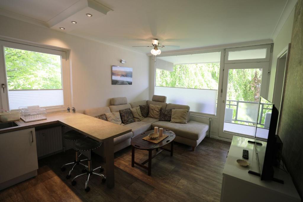 a living room with a couch and a desk and a table at PEMATRA Ferienwohnung Strandmuschel in Travemünde