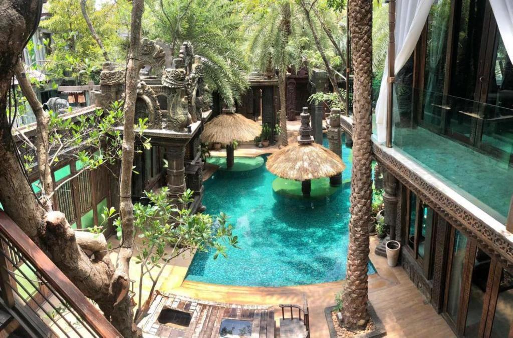 una vista aérea de una piscina con sombrillas y árboles en KhgeMa NuanJun Pool Villa Gallery Resort, en Ban Huai Yai