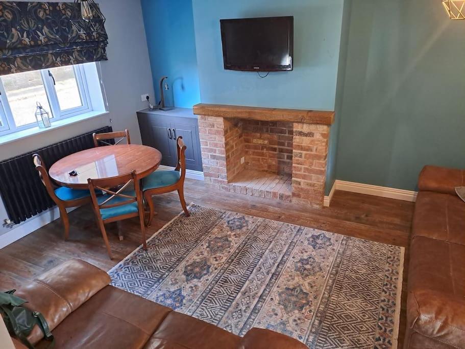 a living room with a table and a fireplace at Cosy cottage near Alton Towers in Rocester