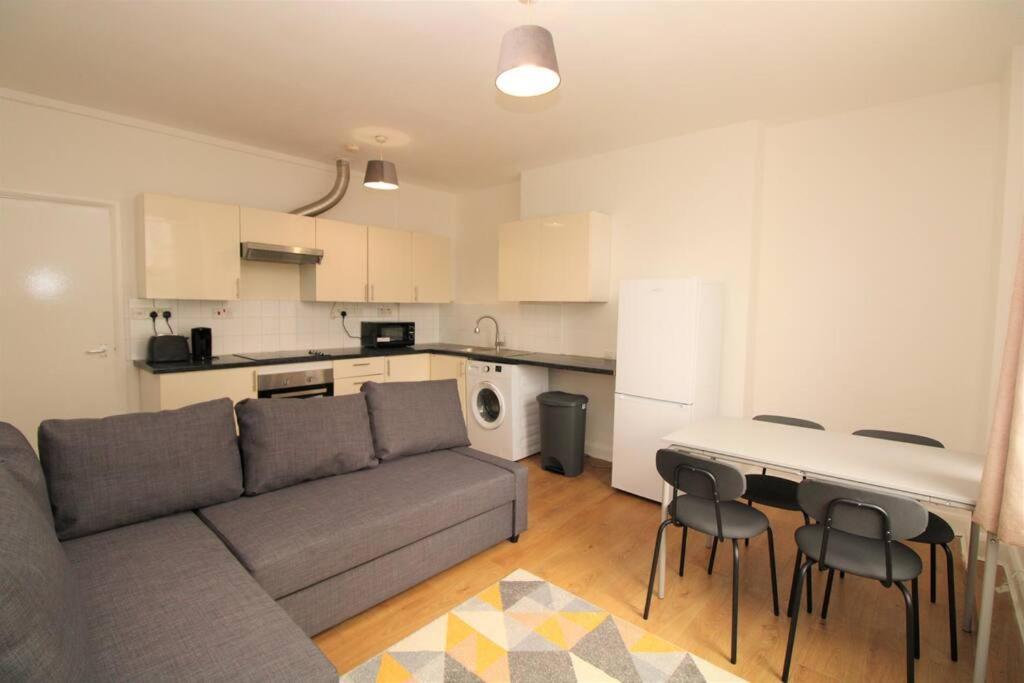 ein Wohnzimmer mit einem Sofa und einer Küche in der Unterkunft Ideal 2 Bed Flat close to City in London
