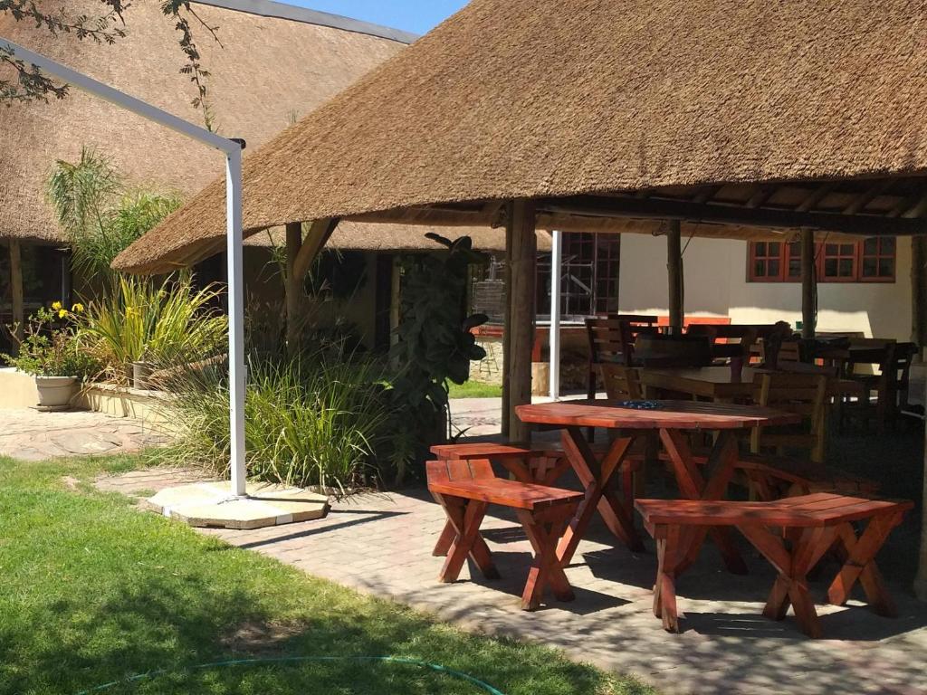 a picnic table and benches under a straw umbrella at Uitkyk Guest Farm in Usakos
