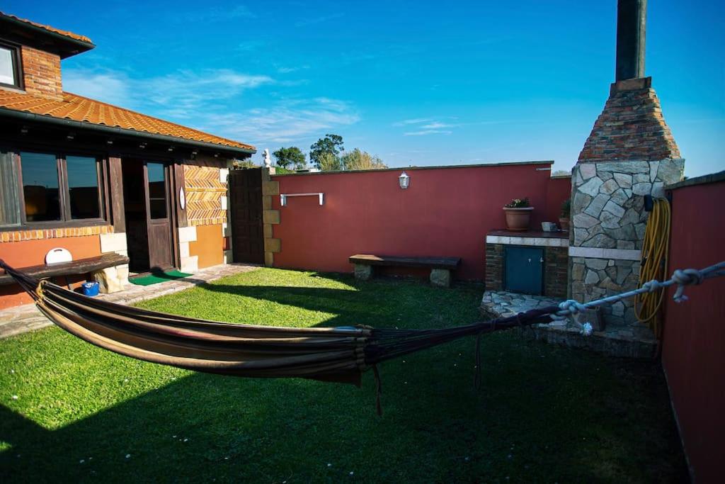 a hammock in a yard next to a house at Casa independiente con chimena, jardín y barbacoa in Santander