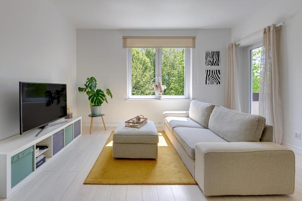 a white living room with a couch and a tv at Downtown Apartments Angielska Grobla Street in Gdańsk