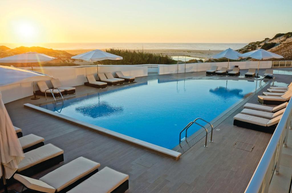 uma grande piscina com cadeiras e guarda-sóis em The Beachfront - Praia D'El Rey Golf & Beach Resort em Praia del Rei