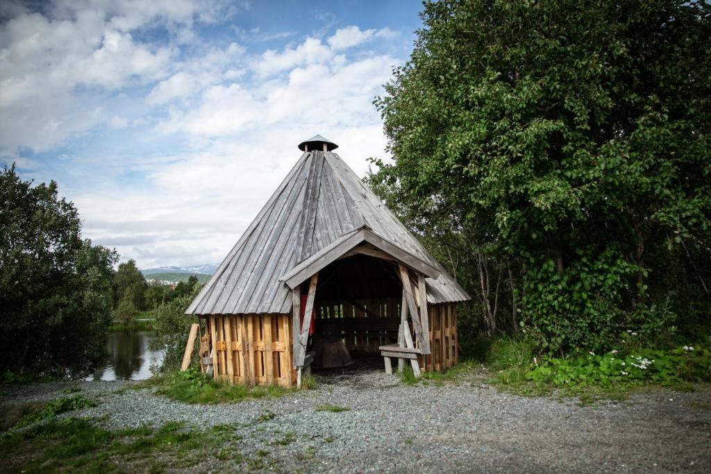 a small building with a roof next to a river at Tromsø Lodge & Camping in Tromsø