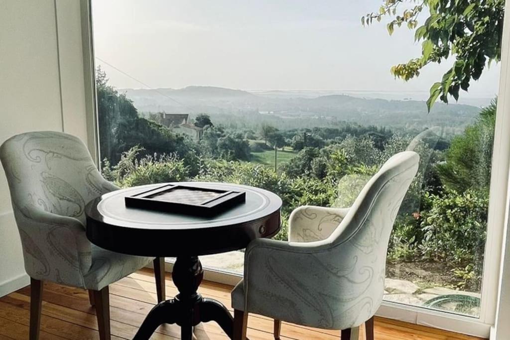 a table and two chairs in front of a window at Moradia na Serra in Alcanede