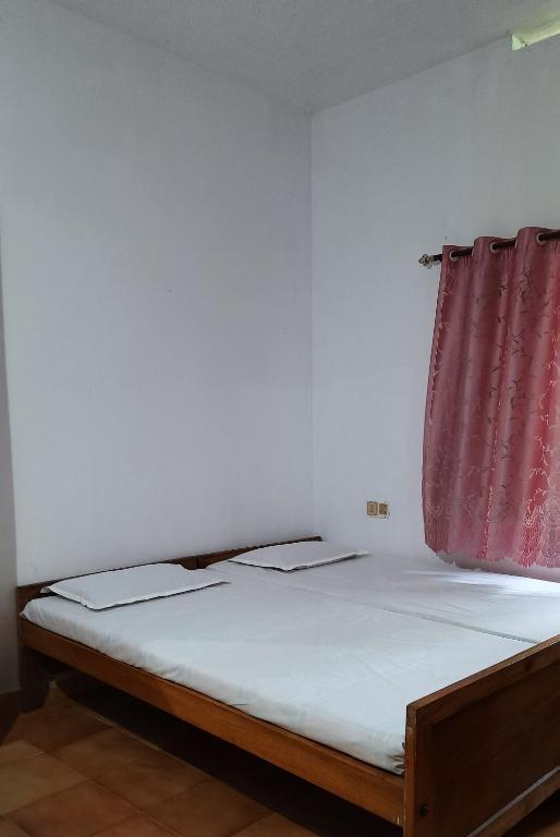 Cama en habitación con cortina roja en Nandanam homestay, en Varkala