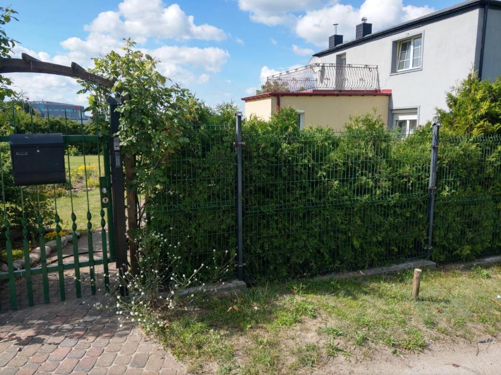 uma cerca em frente a um edifício com uma casa em Apartament u Wuja morze/plaża/ogród/parking em Gdansk