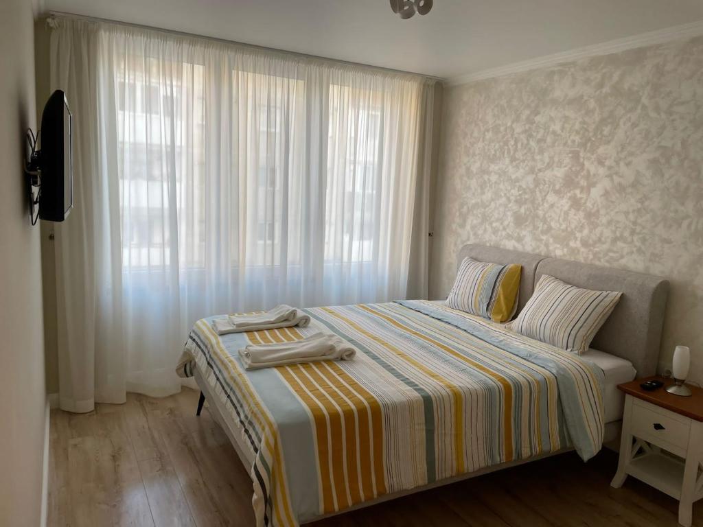 a bedroom with a bed with a striped blanket and a window at Apartament 1 Lalelelor in Năsăud