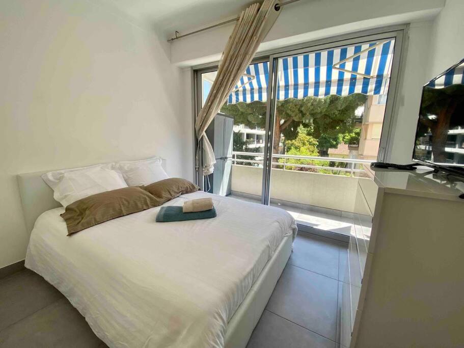 une chambre avec un lit et une grande fenêtre dans l'établissement L'Orangeraie Centre Cannes Martinez, Beau F2 avec terrasse, à Cannes