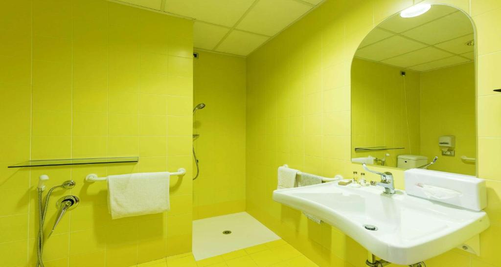 Baño amarillo con lavabo y espejo en Best Western Hotel I Colli, en Macerata