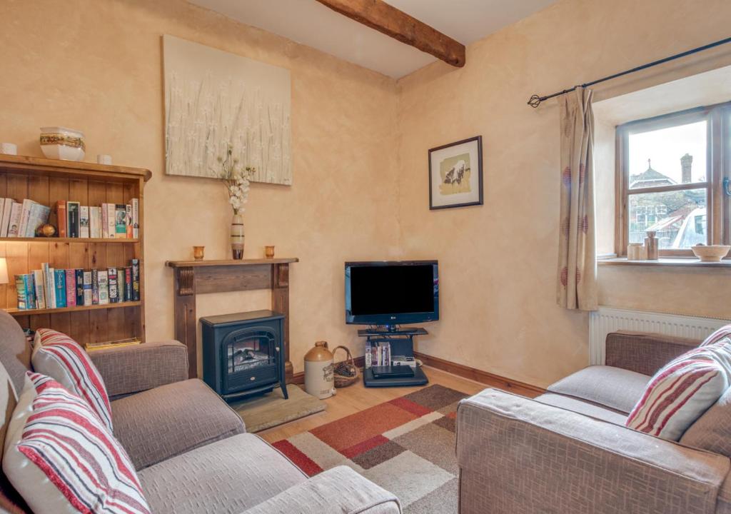 a living room with two couches and a television and a fireplace at Piglet Cottage in Seamer