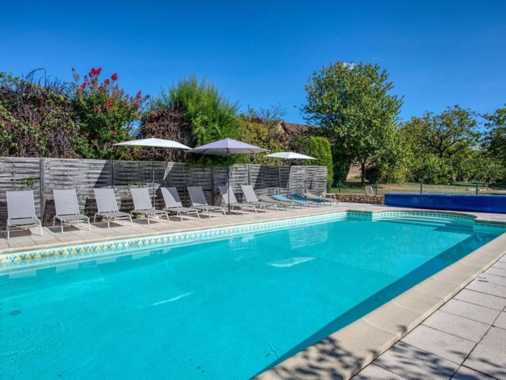 una piscina con sedie e ombrelloni di Gite Les Milandes a Sainte-Mondane