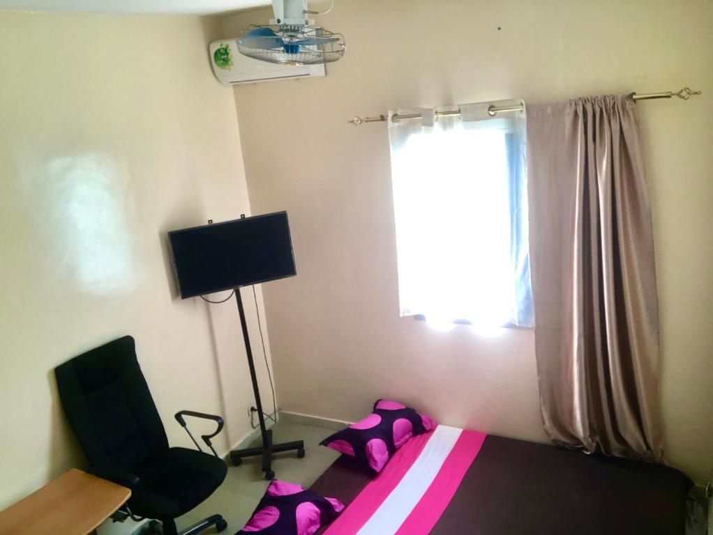 Un dormitorio con una cama y una silla y una ventana. en Chambre Securisée centre Dakar, en Dakar