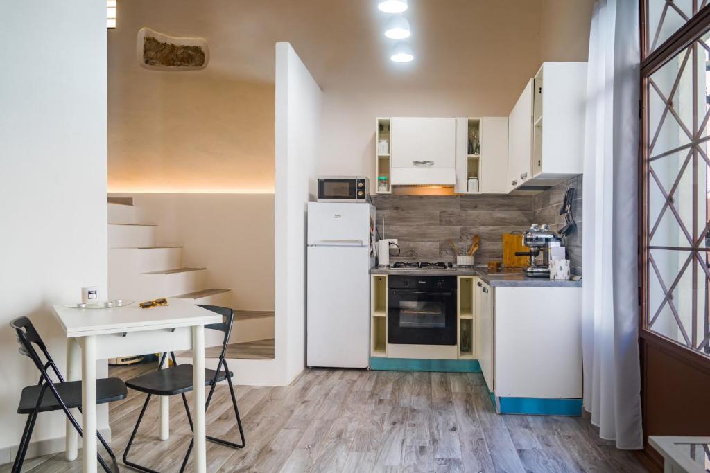 una cucina con armadi bianchi, tavolo e piano cottura di Appartamento Moderno Capoliveri a Capoliveri