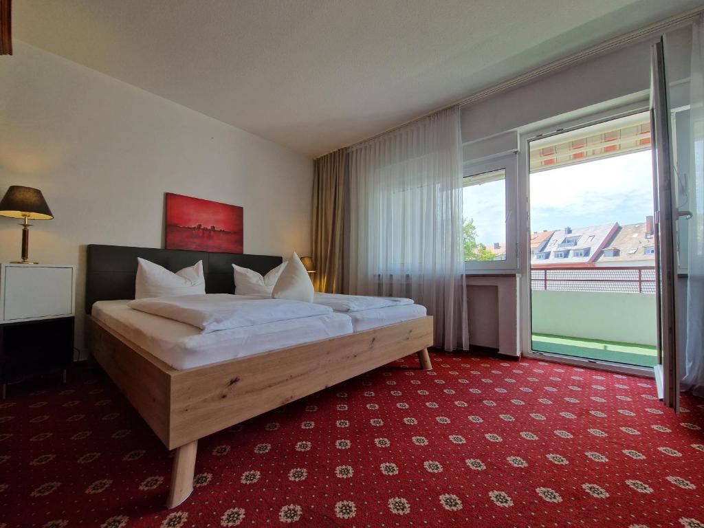 a bedroom with a bed and a large window at Apart Hotel Freiburg in Freiburg im Breisgau