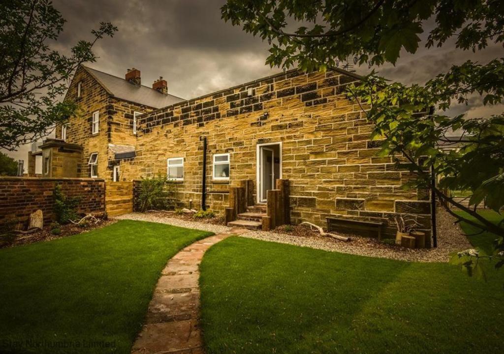 a brick house with a lawn in front of it at Boca Chica Cottage in Cambois