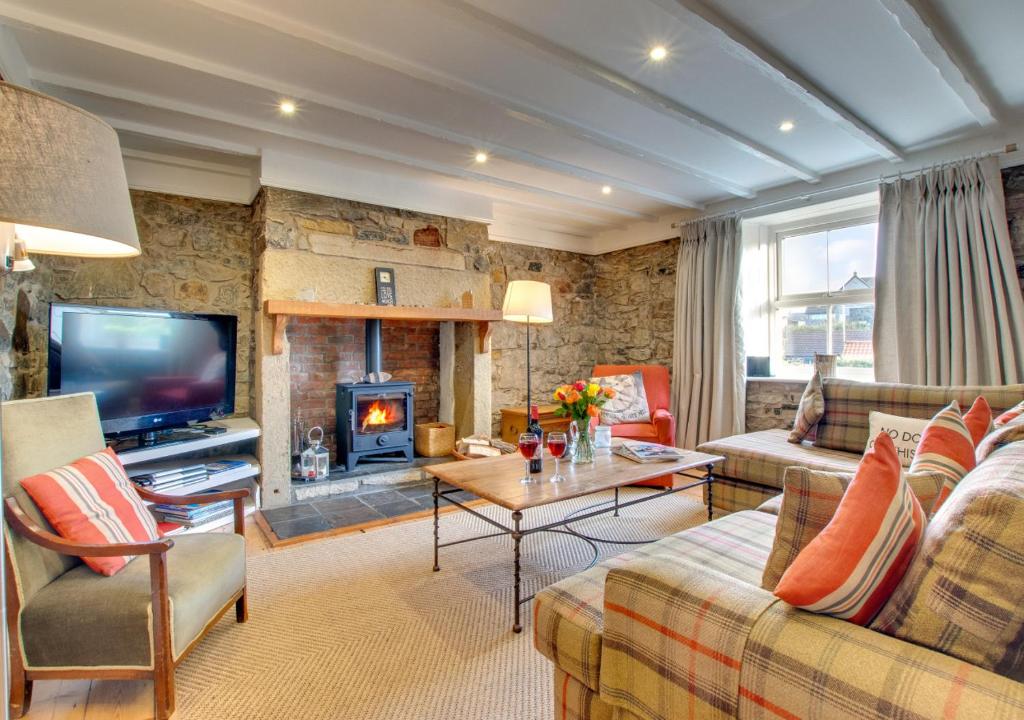 a living room with a couch and a fireplace at Pegasus Cottage in Craster