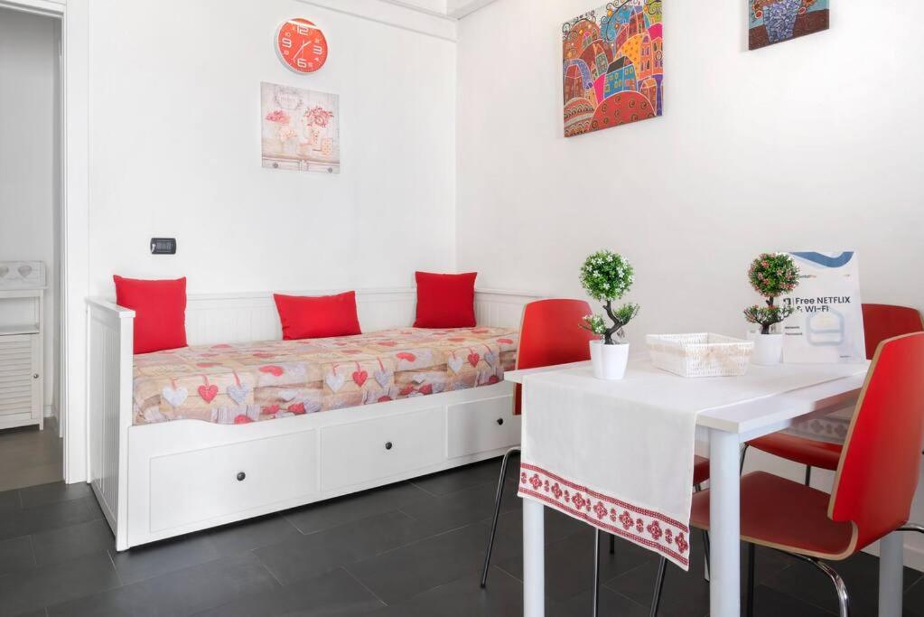 Un dormitorio con una cama con almohadas rojas y una mesa. en Sorres Home & Relax 10 min da Sassari Loft AC e WiFi, en Codrongianos
