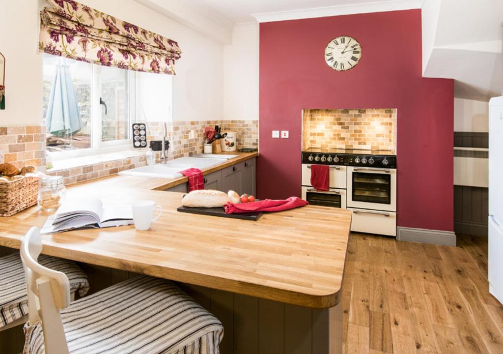 una cucina con tavolo in legno e parete rossa di The Greenhouse a Bamburgh