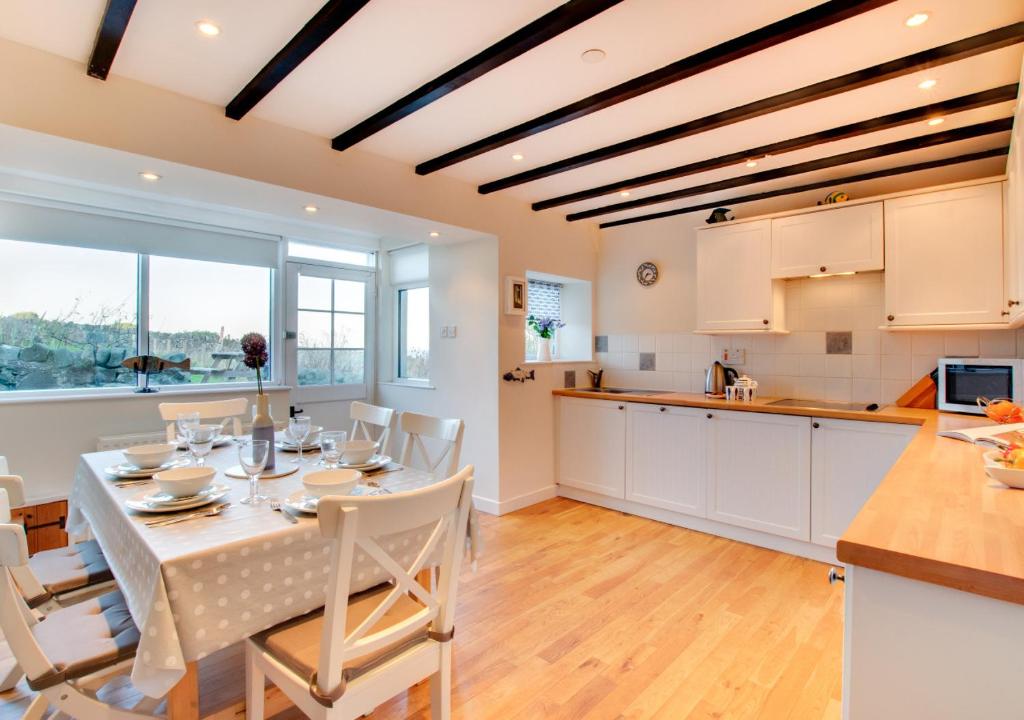 a kitchen and dining room with a table and chairs at Castle Point Cottage Craster in Craster