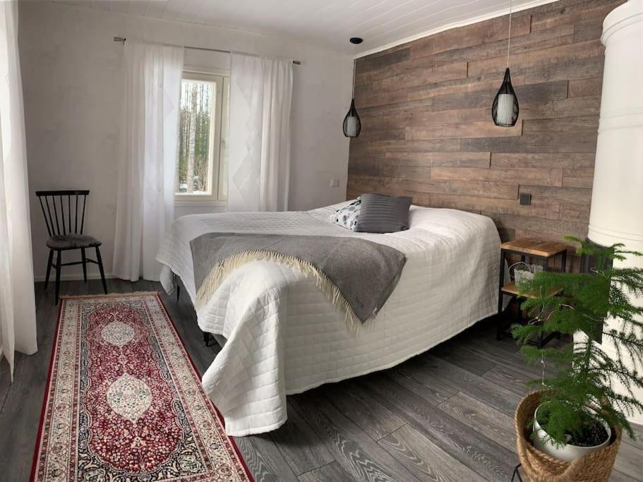 een slaapkamer met een bed en een houten muur bij Talo Pyhä-Häkin kansallispuiston kupeessa in Saarijärvi