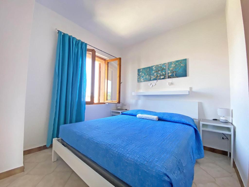 a bedroom with a blue bed and a window at Sunset House La Cinta ST5 - PuntoCasaBudoni in San Teodoro