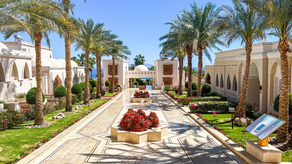 un jardin en face d'un bâtiment avec des palmiers dans l'établissement Club Reef Resort & Spa, à Charm el-Cheikh