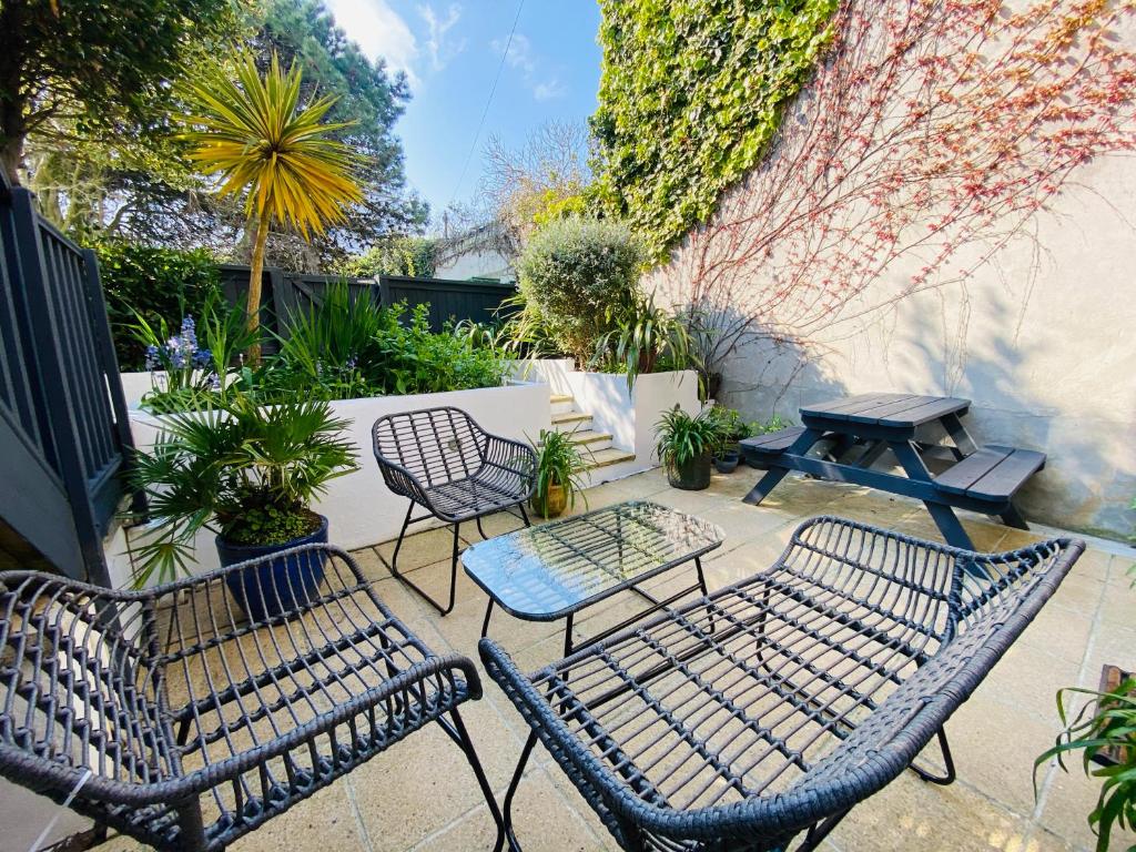 a patio with chairs and a table and a picnic table at "The Garden Apartment Newquay" by Greenstay Serviced Accommodation - Beautiful 2 Bed Apartment With Parking & Outside Terrace, Close To Beaches, Shops & Restaurants -Perfect For Families, Couples, Small Groups & Business Travellers in Newquay