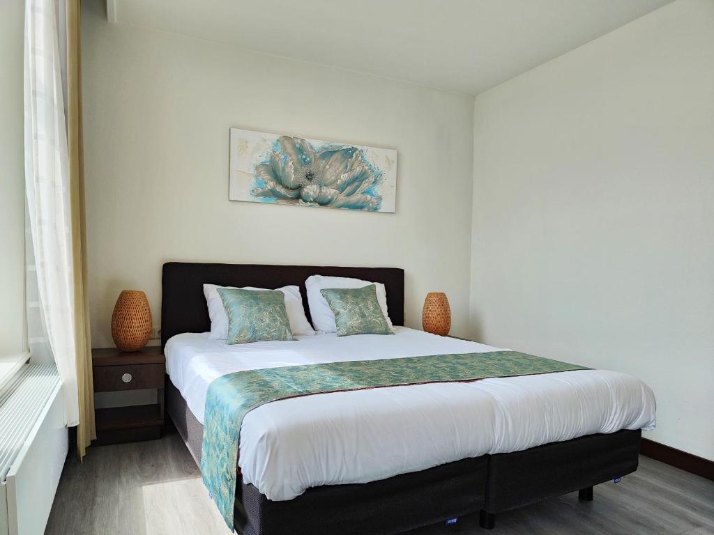 a white bedroom with a large bed with two pillows at CN-Hotel in Arnhem