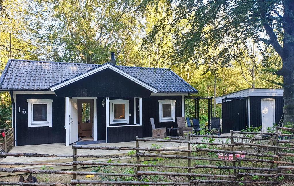 een zwart huisje in een tuin met een hek bij 1 Bedroom Cozy Home In rkelljunga in Orkelljunga