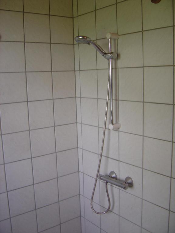 a shower with a shower head in a bathroom at Landstedet in Gram