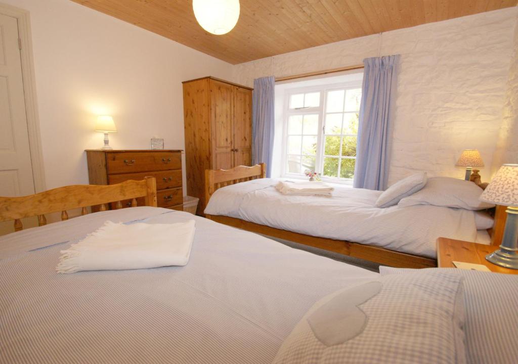 1 dormitorio con 2 camas y ventana en Holmhead Cottage, en Greenhead