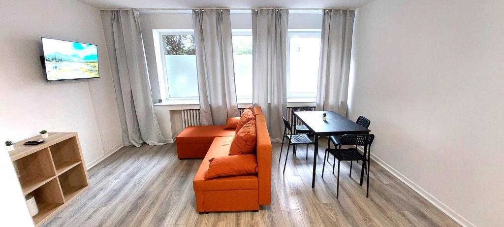 a living room with an orange couch and a table at City Apartments in Neuss