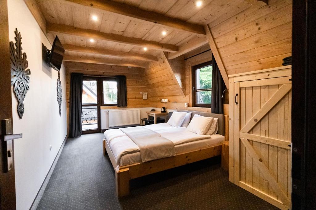 ein Schlafzimmer mit einem Bett in einer Holzhütte in der Unterkunft Chocholowska Zohylina pokoje i domek in Chochołów