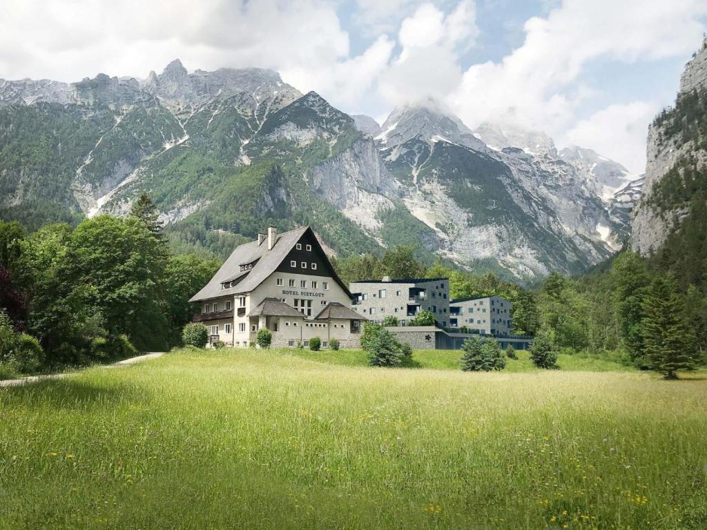 a house in a field with mountains in the background at Dietlgut Natur Resort in Hinterstoder