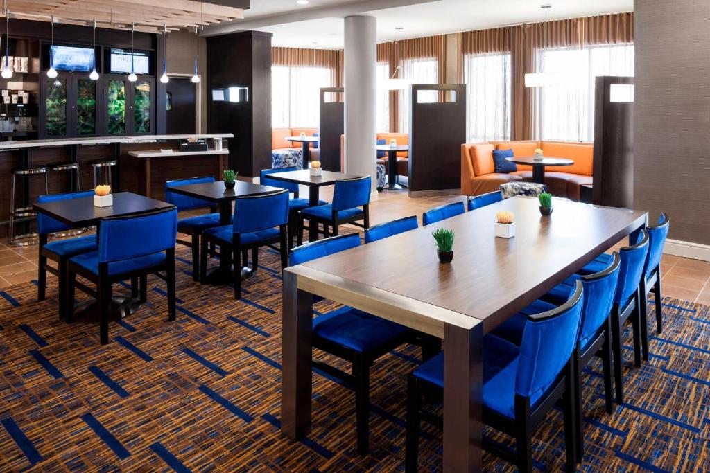 a dining room with tables and blue chairs at Courtyard by Marriott Houston North/Shenandoah in The Woodlands