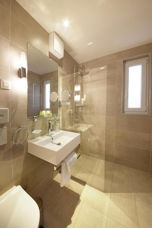 a bathroom with a sink and a toilet and a mirror at Olive Family Suites - Hotel & Resort Adria Ankaran in Ankaran