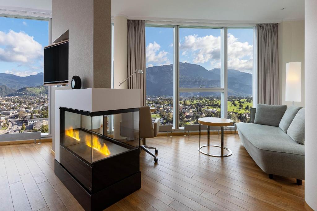a living room with a fireplace with a view of a city at Four Points by Sheraton Panoramahaus Dornbirn in Dornbirn