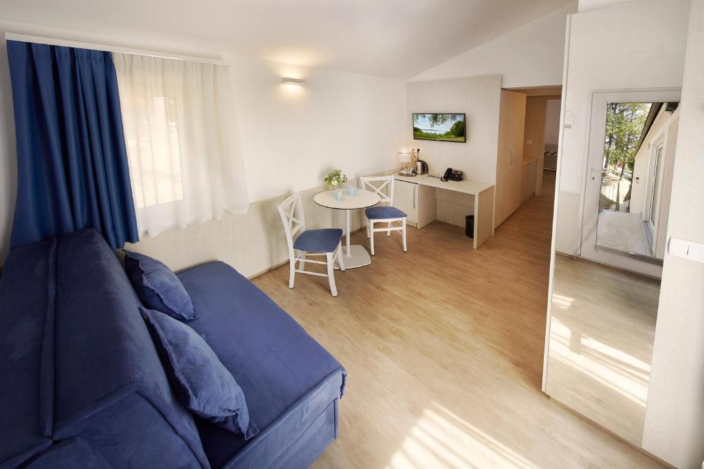 a living room with a blue couch and a table at Olive Family Suites - Hotel & Resort Adria Ankaran in Ankaran