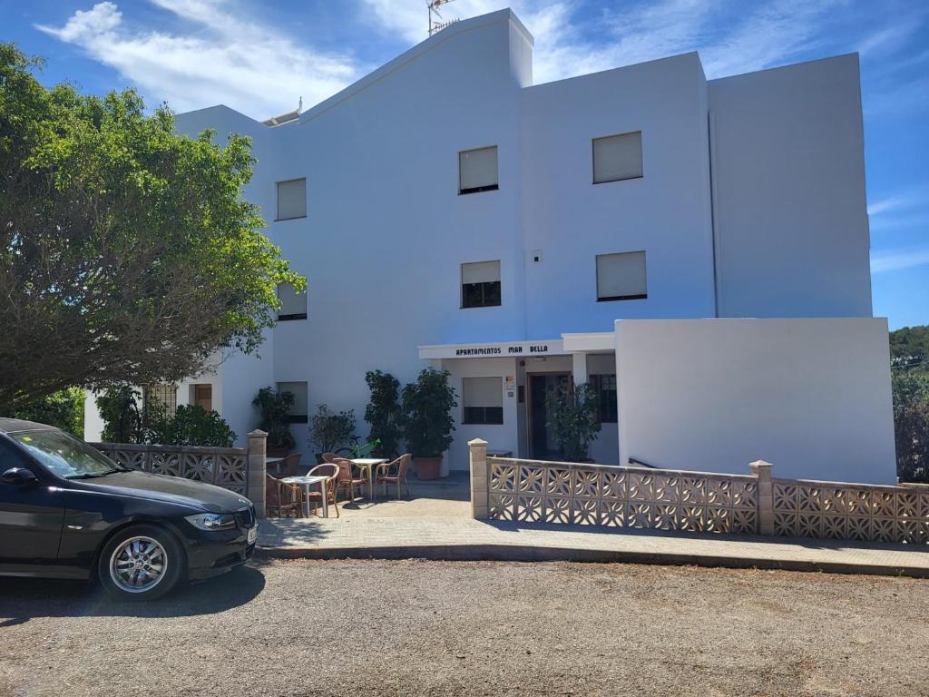 ein weißes Gebäude mit einem davor geparkt in der Unterkunft Apartamentos Mar Bella in Es Cana