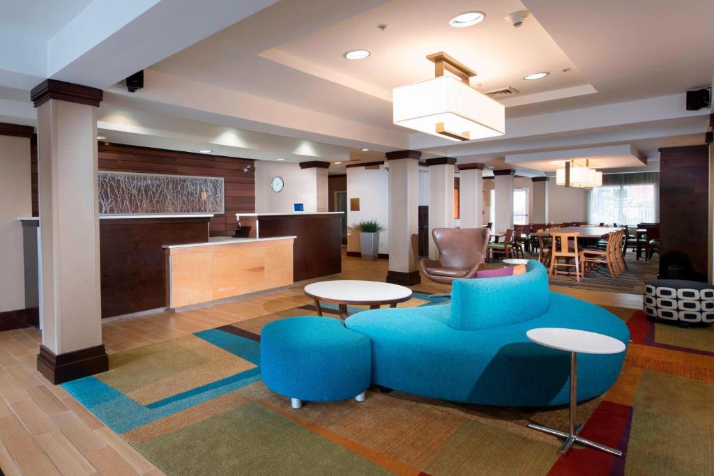 vestíbulo con sofá azul, mesa y sillas en Fairfield Inn and Suites Charleston North/University Area, en Charleston