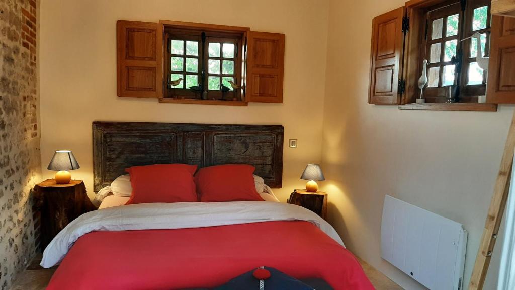 a bedroom with a bed with red pillows and windows at Le Parc aux Oiseaux in Le Mesnil-Simon