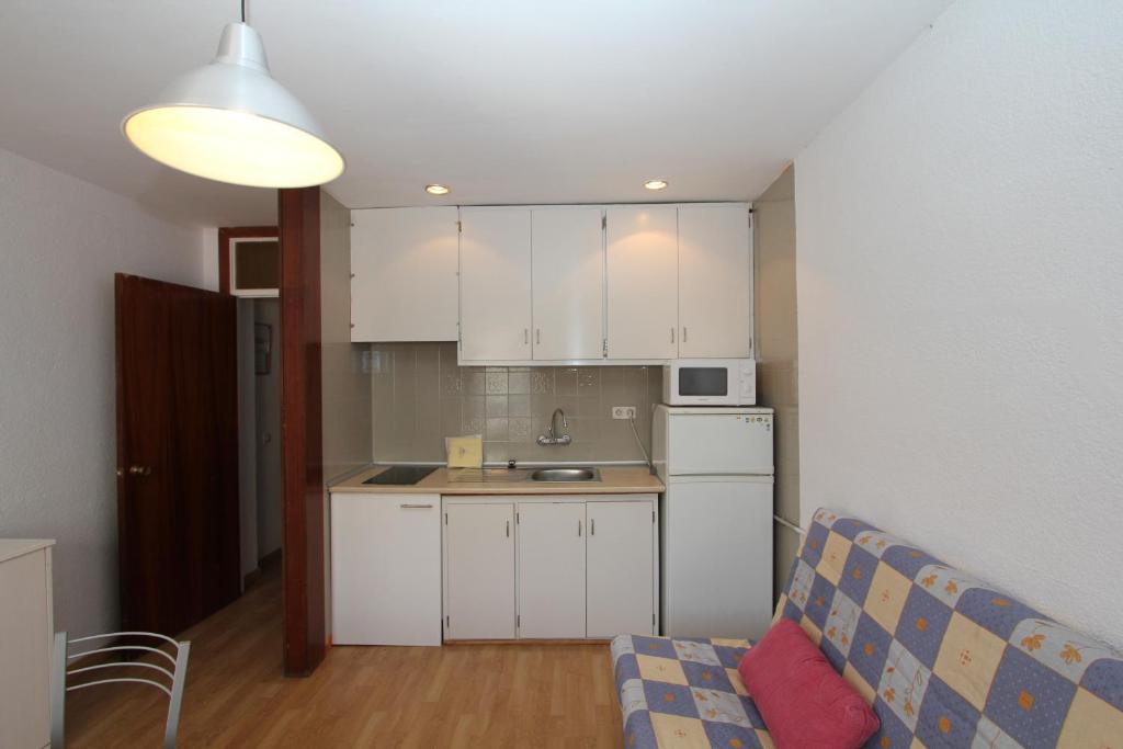 - une cuisine avec des placards blancs et un canapé dans la chambre dans l'établissement Apartamento Holanda, à Lloret de Mar