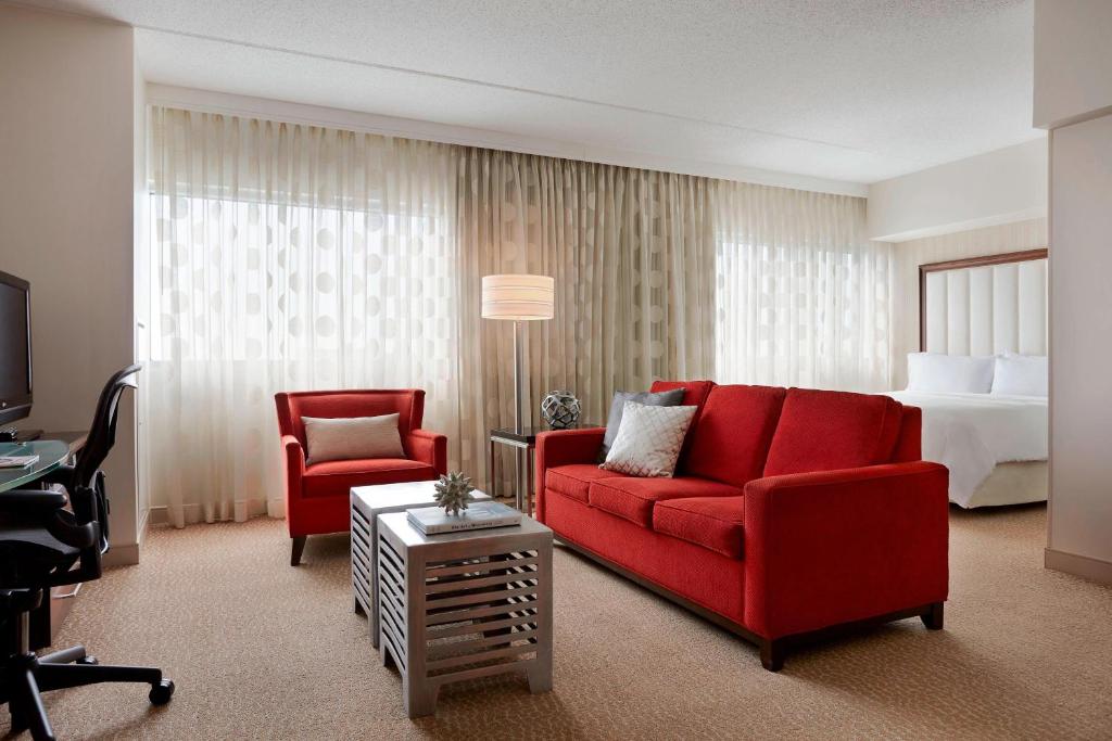 a hotel room with a red couch and a bed at Renaissance Newark Airport Hotel in Elizabeth